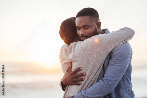 Content young African couple embracing each other at the beach