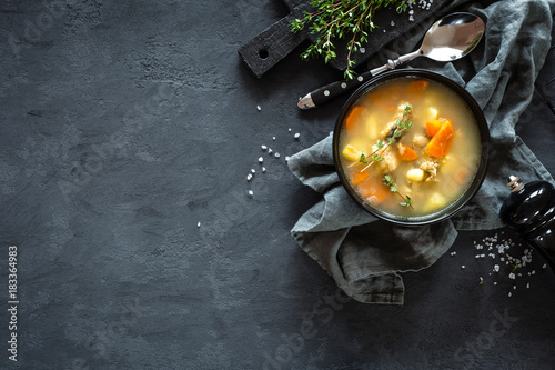 Fresh fish soup in bowl on dark background, top view