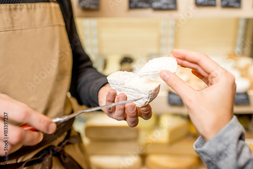 Cutting a cheese for woman customer at the food store