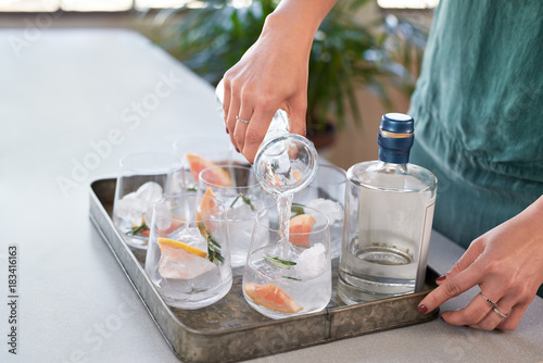 Woman making gin tonic cocktails at party