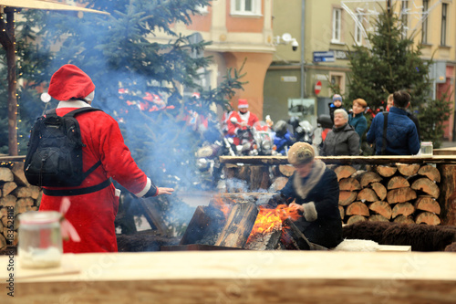 Święty Mikołaj grzeje dłonie przy ognisku na rynku w Opolu.