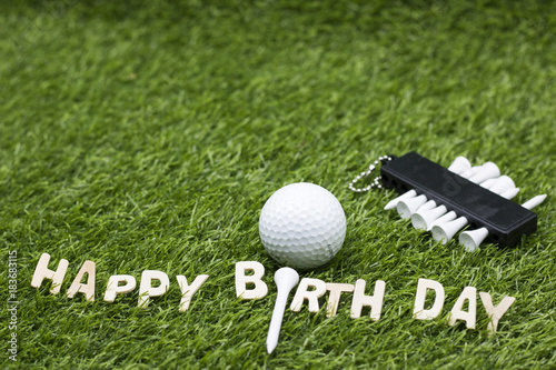Happy birthday to golfer lettering on green grass with golf balls and tee