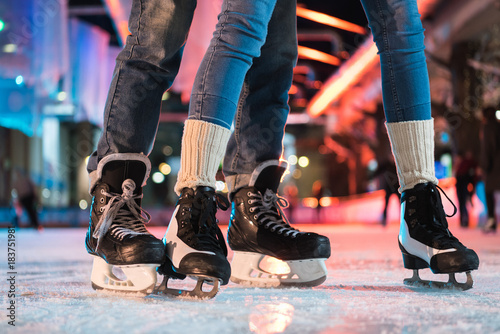 close-up partial view of young couple in skates ice skating on rink