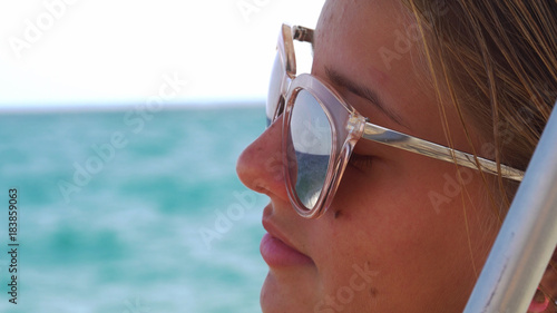 Beautiful young girl in the sunglasses in the sea