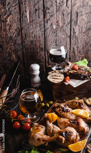 tasty grilled meat with vegetables and beer on wooden background