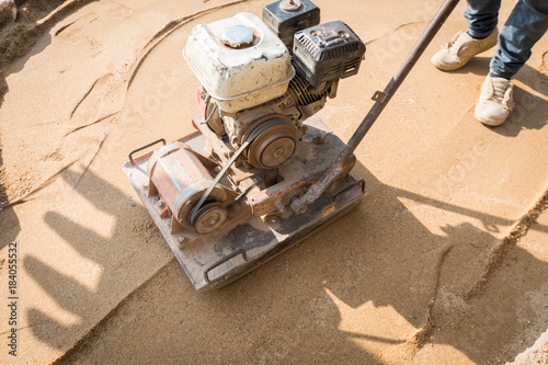 worker with plate compactor on construction site