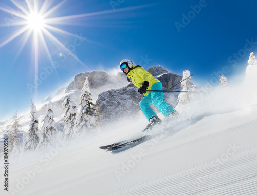 Young woman skier running down the slope in Alpine mountains.