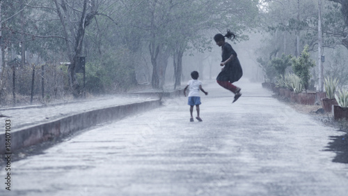 Mother and daughter welcoming the first monsoon showers by playing in heavy rain
