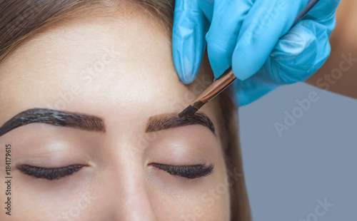 makeup artist applies paint henna on previously plucked, design, trimmed eyebrows in a beauty salon in the session correction. Professional care for face.