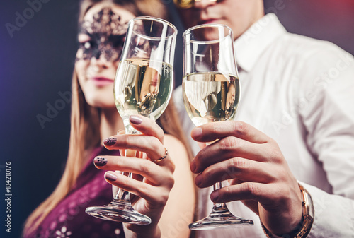 Couple celebrating New Year's eve drinking champagne on masquerade party