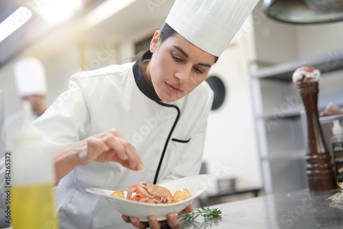 Closeup of cook chef in professional kitchen preparing dish