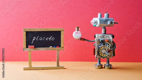 Placebo effect concept Medic robot drugs tube, black chalkboard with handwritten word placebo. Pink wall brown floor background.