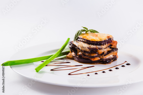 eggplants parmigiana with cheese and tomato traditional recipe on a white plate on a light background (close top view)
