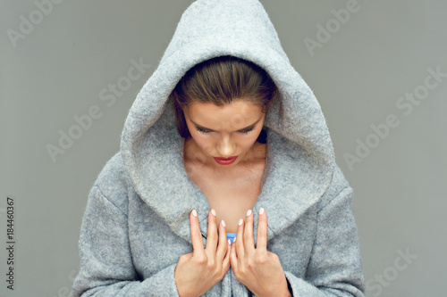 Young woman wearing hood looking down.