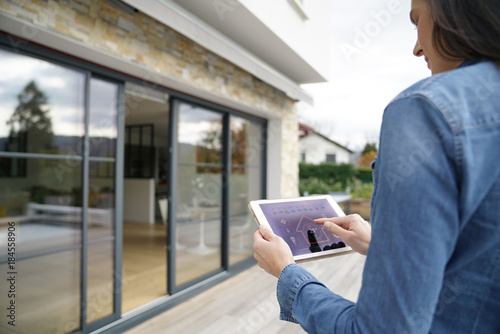 Woman using remote home control system on digital tablet