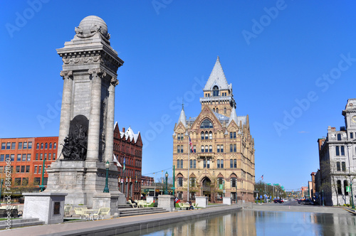 Soldiers' and Sailors' Monument and Syracuse Saving Bank Building at Clinton Square in downtown Syracuse, New York State, USA. Syracuse Savings Bank Building was built in 1876 with Gothic style.