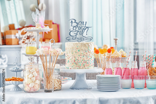 "Boy or girl" cake and different treats for baby shower party on table indoors