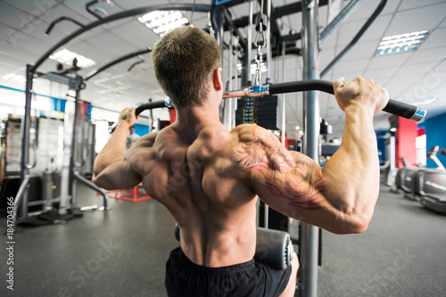 Shoulder pull down machine. Fitness man working out lat pulldown training at gym. Upper body strength exercise for the upper back.