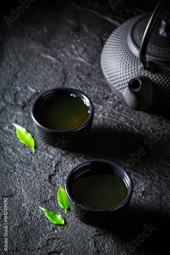 Fresh green tea in teacup on black rock