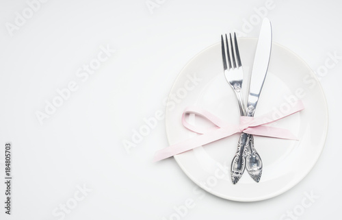 composition for Valentine's day knife and fork tied with ribbon on a plate with decorative hearts