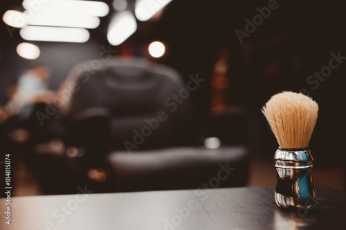 brush for shaving beard along with bowl, blurred background of hair salon for men, barber shop