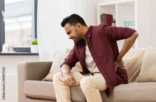 unhappy man suffering from backache at home