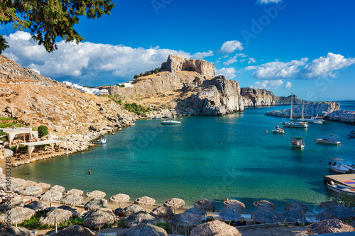 Beautiful St. Paul´s bay with boats, Lindos acropolis in background (Rhodes, Greece)