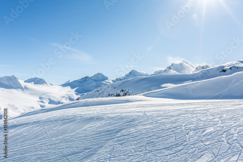 Off-piste ski slope with trace from skis and snowboards at sun winter day. Kavkaz mountains.