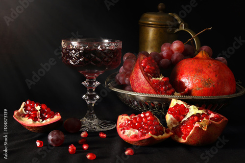 Still life with pomegranates, grapes and a glass of wine