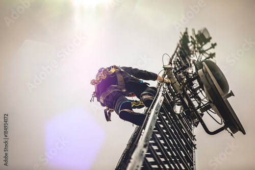 Telecom Worker Climbing Antenna Tower with Harness and Tools