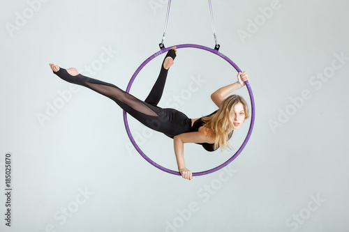 Woman aerial acrobat performs with tricks on the hula hoop at the top.