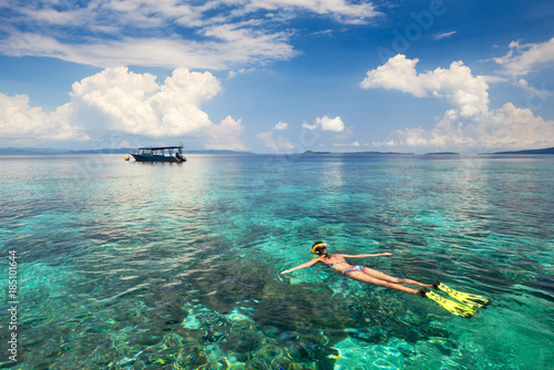 Woman snorkeling in clear tropical waters on a background of islands