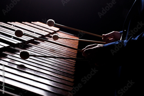 The hands of a musician playing the marimba in dark tones