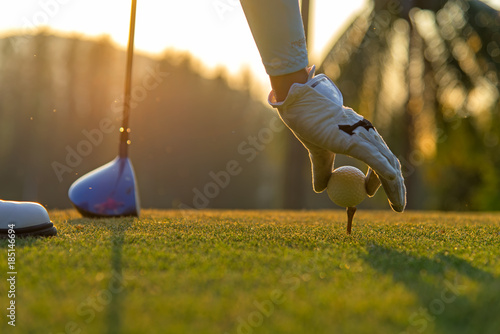 Wręcza azjatykciej kobiety kładzenia piłkę golfową na trójniku z klubem w polu golfowym na wieczór i zmierzchu czasie a dla zdrowego sporta. Koncepcja stylu życia.