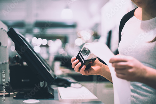 Young saleswoman taking a stamp with discount / sale to receipt (color toned image)