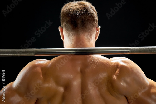 Professional athlete lifting a barbell. Sweat over relief muscular body. Squats and weightlifting.
