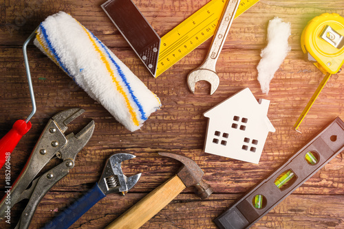 Wooden white house toy and construction tools on wooden background with copy space.Real estate concept, New house concept, Finance loan business concept, Repair maintenance concept.