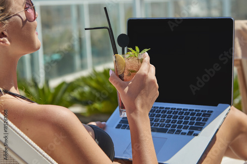 Kobieta pracująca na laptopie. Dziewczyna na wakacjach. Praca w podróży. Praca zdalna. Na basenie.