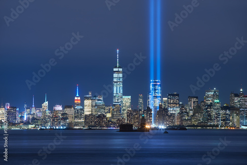 The two beams of the Tribute in Light with skycrapers of Lower Manhattan at night from New York Harbor. Financial District, New York City