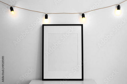 Mockup of blank frame with garland on light background
