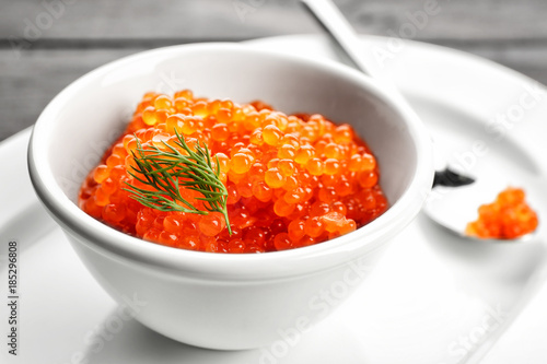 Bowl with delicious red caviar on table