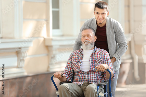 Young caregiver walking with senior man, outdoors