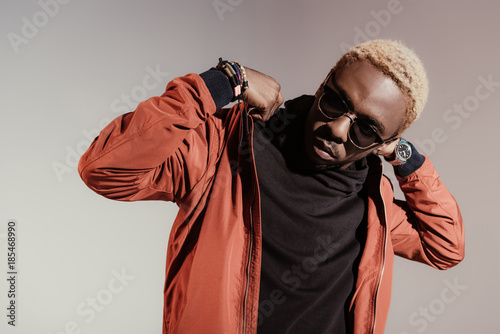 Stylish young african american man straightens his jacket isolated on light background