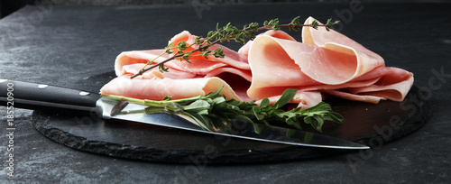 Sliced ham on stone background. Fresh prosciutto. Pork ham sliced.