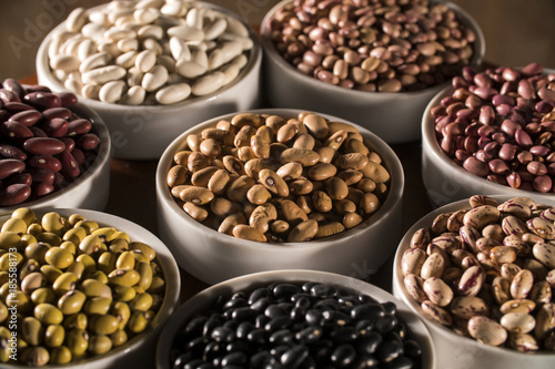 Assorted beans in bowls on wood background