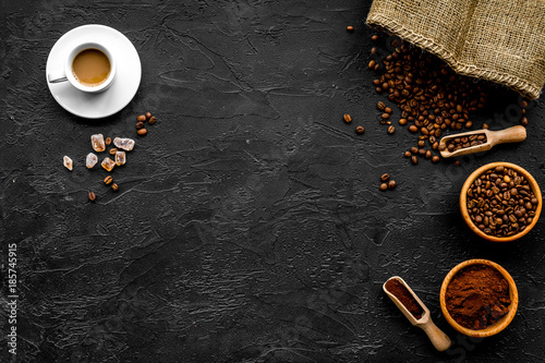 Coffee concept. Roasted beans, ground coffee, cup of espresso and sugar on black background top view copyspace
