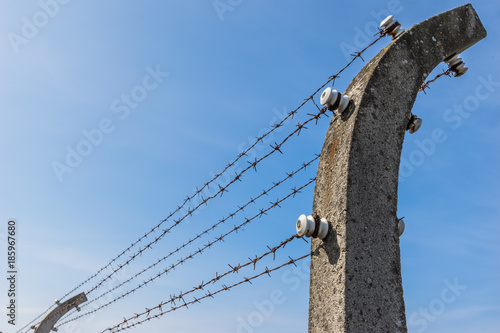 Konzentrationslager KZ / Elektro Stacheldrahtzaun vor blauem Himmel 