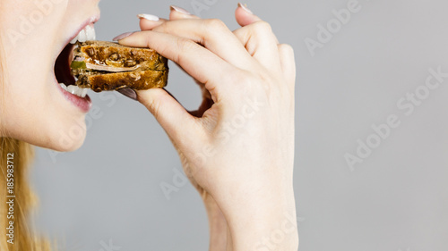 Woman eating sandwich, taking bite