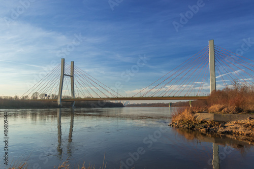 Siekierkowski suspension bridge across the Vistula river with its reflection in water on a sunny day