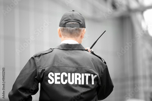 Male security guard using portable radio outdoors